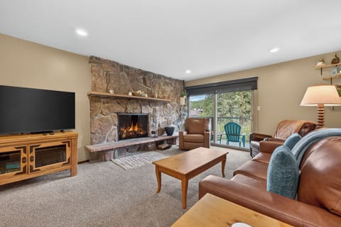 Sink into plush leather seating and warm your toes by the crackling stone fireplace. Your cozy retreat features modern entertainment, inviting natural light, and serene mountain views just beyond your private balcony.