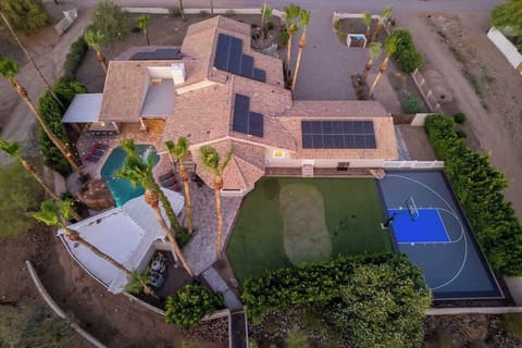 This desert oasis features a spacious layout with pool, sport court, putting green, and modern solar panels—all set within a quiet residential neighborhood lined with palm trees.