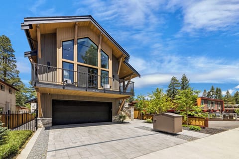 A modern mountain retreat with sleek architecture, private balcony, and attached garage—nestled in a peaceful neighborhood surrounded by towering pines and blue skies.