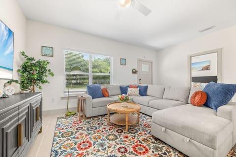 Spacious, sunlit living room featuring a large sectional, smart TV and games