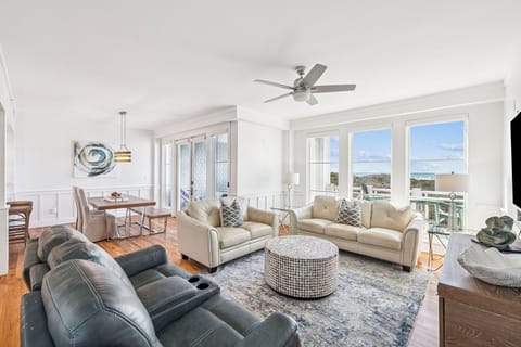 Picture yourself relaxing in this bright, airy living space where coastal breezes flow through open windows and natural light fills every corner, offering stunning views of the sea and shore.