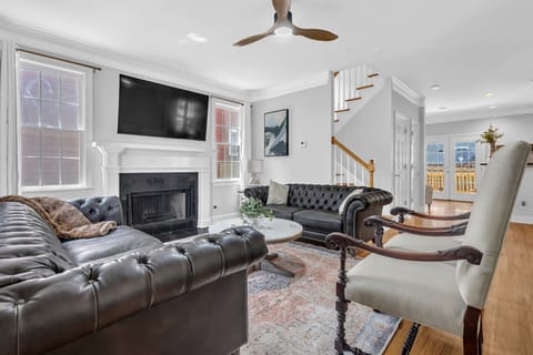 Elegant living room with leather seating, fireplace, and large TV