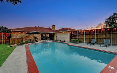 Resort-style backyard with a sparkling pool, lounge seating, and twinkling café lights—perfect for sunset swims and evening relaxation.