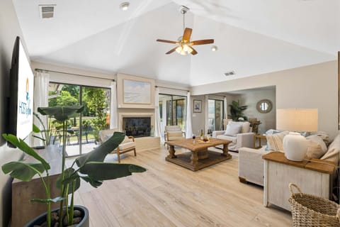 The open-concept living room is filled with natural light and showcases beautiful views of the golf course through expansive windows and sliding glass doors.