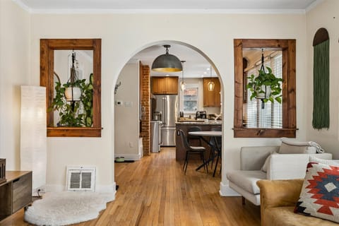 Interior view of a classic archway and built-in shelving nooks decorated with hanging indoor plants and natural wood trim.