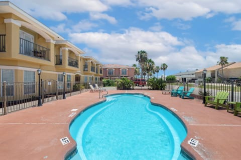 The property features an inviting outdoor pool area surrounded by comfortable seating and swaying palm trees, perfect for soaking up the sun in a warm, relaxed atmosphere.