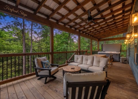 Covered forest-view deck with hot tub, lounge seating, and outdoor dining
