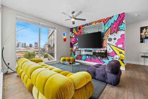 - Bold mural wall with mounted TV  
- Plush modern sectional for groups  
- Floor to ceiling windows with light  