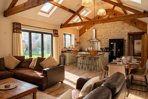 Sunlit open plan living with vaulted beams, stone wall and a sociable island kitchen.