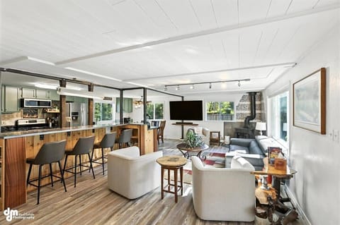 Open floorplan is bathed in natural light; incorporates kitchen, custom island bar, dining, fireplace and Roku TV for relaxing or easy entertaining.