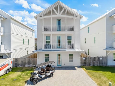 3-story beach house with dual balconies, FREE 6-seat golf cart, and a charming coastal exterior—steps from Miramar Beach's sugar-white sands and emerald waters.