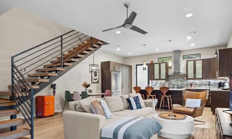 Gather in the open-concept living space where the lounge, kitchen, and dining flow together under a striking floating staircase.