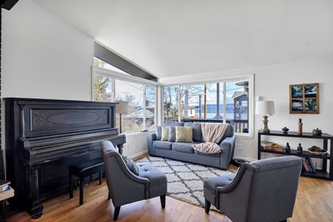 Bright living room with piano, cozy seating, and beautiful water views