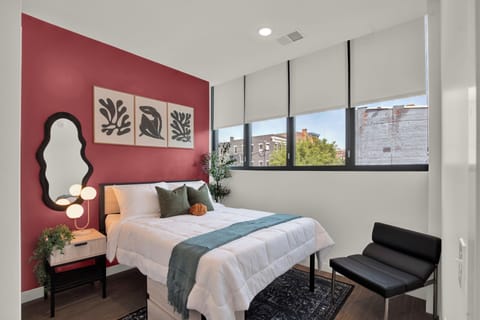 Bright modern bedroom with bold accent wall and large city-view windows