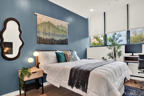 Cozy modern bedroom with bold accent wall, desk space, and natural light