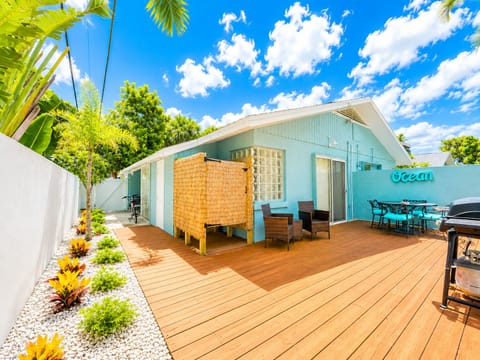 Sunny tropical deck with outdoor dining, grill, and private patio seating