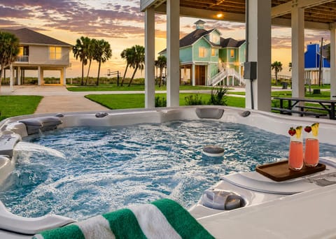 Unwind in a private bubbling hot tub at this Galveston beach house. Covered outdoor spa area with coastal views, tropical vibes, and the perfect relaxing getaway amenity.