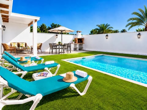 Sunny private pool area with turquoise sun loungers, BBQ dining space, and a bright tropical garden setting.