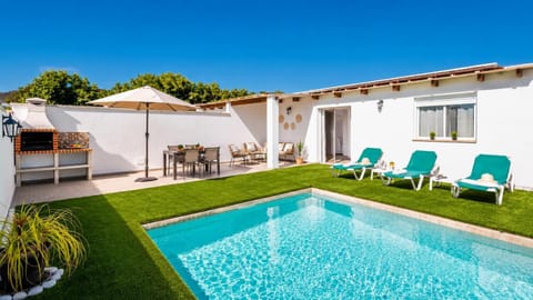 A sunny villa pool terrace with loungers, outdoor dining, and a built-in barbecue area.