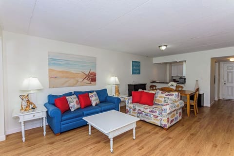 Bright coastal living room with open layout, wood floors, and comfy seating