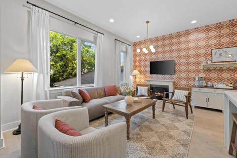 Spacious living area featuring a statement accent wall, electric fireplace, sectional seating, and smart TV.