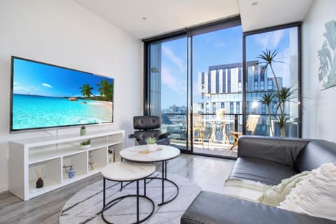 Bright modern lounge with balcony, city views, and floor-to-ceiling windows