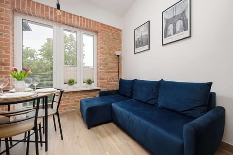Bright studio living area with a comfortable sofa, dining table, and large window.