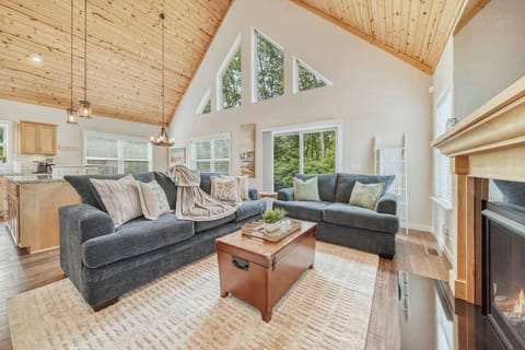 Cozy family room with lots of natural light with large windows, vaulted ceilings, and warm woodwork