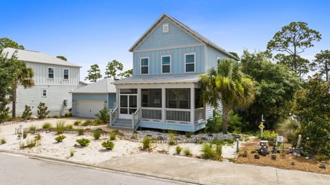 Charming coastal home with covered porch, garage, and beachy landscaping