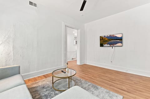Bright, minimalist lounge with wall-mounted TV and warm wood floors