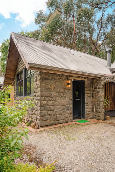 Charming stone cottage retreat amid trees with warm, inviting entry.