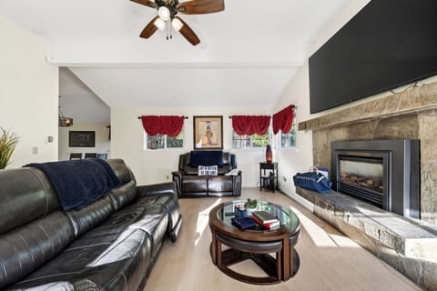 Spacious living room with leather seating, a stone fireplace, and plenty of room to unwind. 