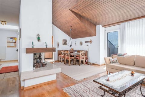 Bright alpine living room with warm wooden ceilings, comfortable seating, a dining area, and large windows.
