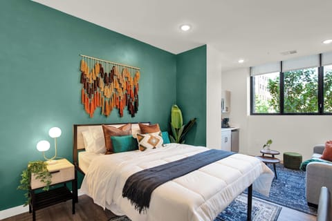 Stylish teal-accent bedroom with natural light, seating area, and modern flair