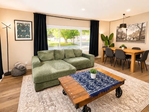 Sunny, inviting living room with plush sectional seating, dining table for 6, and large windows that fill the space with natural light.