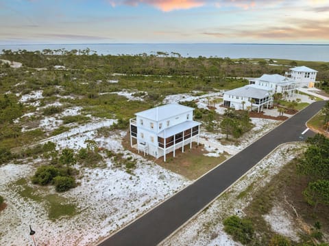 Elevated coastal property showcasing modern architecture with panoramic views of the surrounding natural landscape and nearby waterfront, set within a tranquil beachside community.