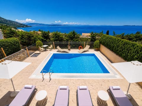 Private pool terrace with sun loungers, umbrellas, and breathtaking panoramic sea views.