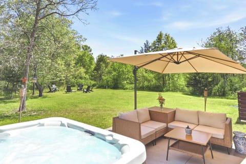 Unwind in a private backyard retreat with a bubbling hot tub, shaded lounge seating, and peaceful green views made for slow mornings and starlit evenings.