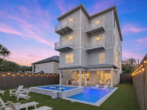 Modern multi-story coastal home featuring private balconies and a luxury backyard pool oasis at dusk.