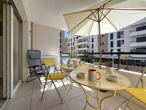 Un matin en ville : le parasol déploie son ombre, la table jaune attend les cafés fumants, un coin convivial pour commencer la journée au calme, face à la cour intérieure.