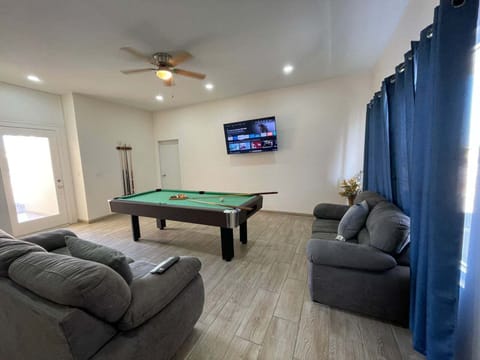 An interior shot of the spacious living room and entertainment area inside La Kasa #1, featuring a comfortable sitting area, a flat-screen television, and a premium snooker table for guest entertainment.