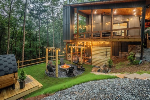 Cozy forest cabin with lit deck, fire pit lounge, and dreamy string lights