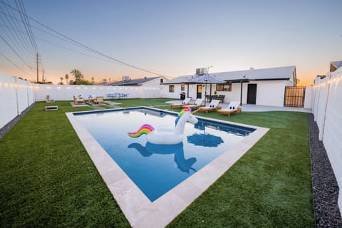 Resort-style backyard oasis featuring a sparkling, pristine swimming pool, manicured turf lawn, and premium lounge spaces.