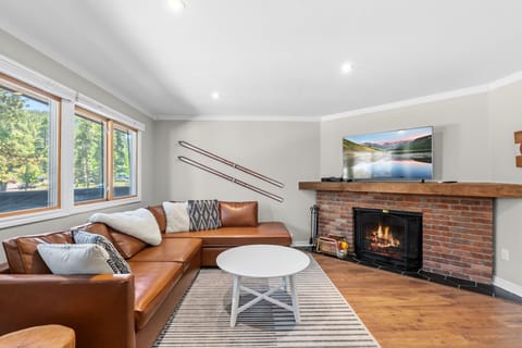 Relax in your spacious living room featuring a cozy fireplace, comfortable seating, and natural light streaming through large windows, creating the perfect retreat after a day of adventure.