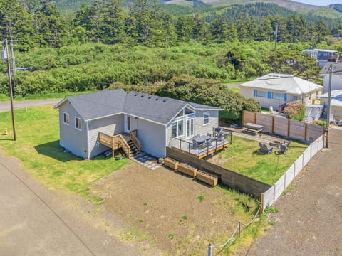 Aerial view of the property nestled in a quiet coastal neighborhood, surrounded by lush greenery and forested mountains.