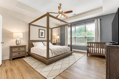 Primary bedroom with four-poster king bed, crib, and large windows.