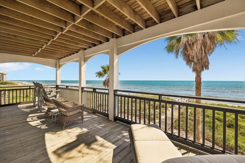 A covered beachfront patio offers stunning Gulf views framed by swaying palms. Relax in your lounge chair as gentle sea breezes drift through this shaded outdoor retreat.