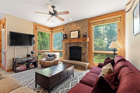 Settle into your inviting living room with warm stone fireplace and rich burgundy sofa. Large windows frame forest views while you relax or gather with loved ones.