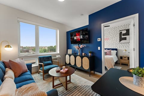 Bright and stylish living area with skyline views, cozy seating, smart TV, and modern décor.