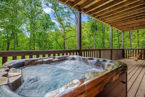 Relax in the bubbling hot tub beneath the covered deck, surrounded by peaceful woodland views and the soothing sounds of the Smoky Mountains.
